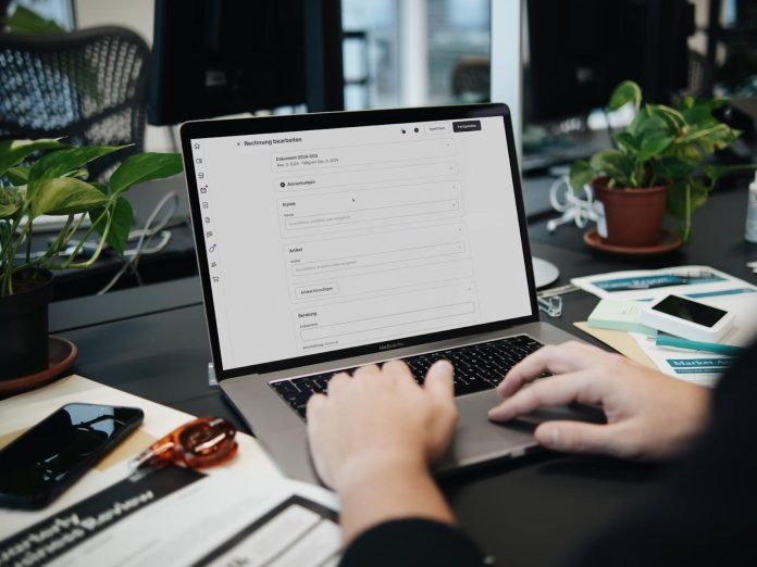 Person using invoicing software on a laptop in an office environment
