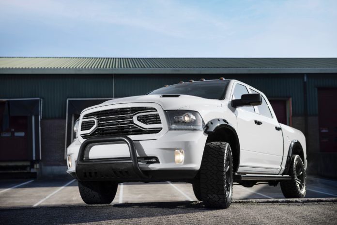 Lifted white pickup truck in front of industrial warehouse.