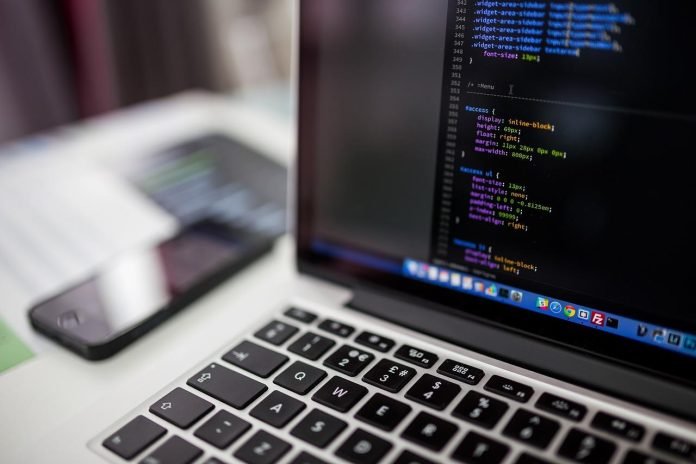 Laptop screen showing CSS code for website migration tasks.