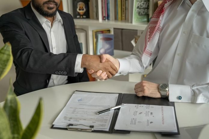 Businessmen shaking hands over financial documents