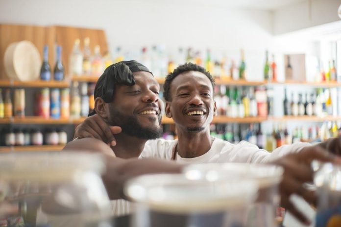 Regulatory Challenges in Alcohol Payment Solutions Two men smiling behind counter in a liquor store.