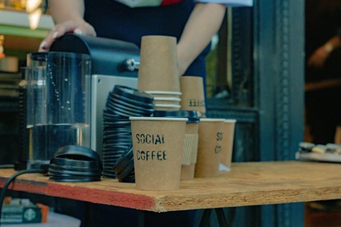 Branded coffee cups at a coffee shop counter with a machine.