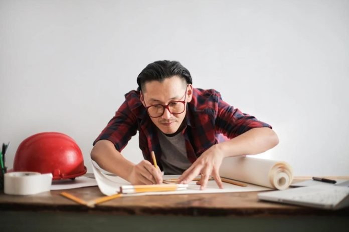 Construction expert drafting legal documents beside safety gear